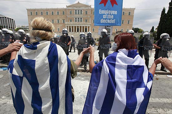 Manifestantes usam bandeira grega em protesto contra medidas de austeridade aprovadas no Parlamento