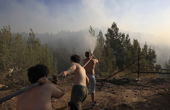 Jovens jogam água e, esforço para conter incêndio florestal em Jerusalém, que forçou retirada de memorial