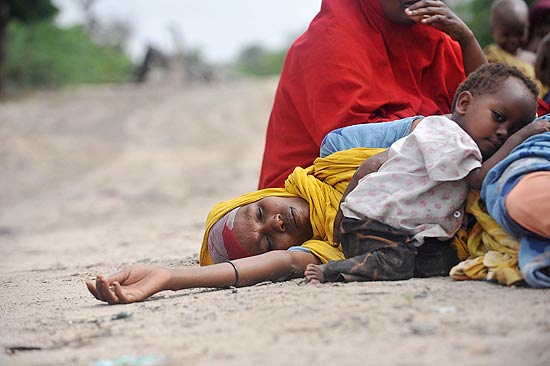 Mulher refugiada aguarda atendimento médico com o filho em acampamento na capital somali, Mogadício