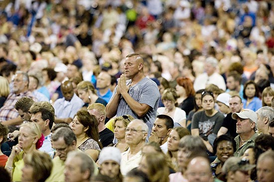 Homem ora no meio da multido no evento do republicano presidencivel,Rick Perry, chamado "A Resposta" 
