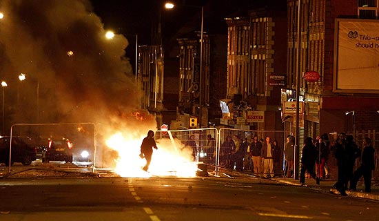 Homem caminha prximo a barricada em Liverpool na quarta noite de violncia no Reino Unido