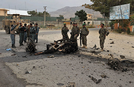 Foras de segurana afegs observam o que restou de um carro-bomba usado em ataque contra gabinete do governador de Charikar