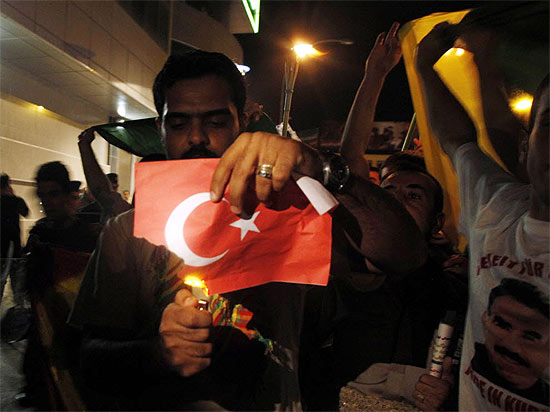 Manifestante queima bandeira da Turquia em protesto contra ataques militares do pas no norte do Iraque