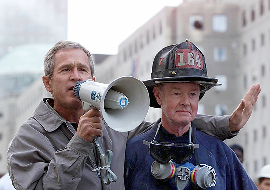 Ao lado de bombeiro aposentado, presidente George W. Bush (esq.) discursa a voluntrios que trabalham nas torres gmeas