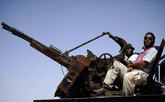 Combatente rebelde descansa em cima de tanque militar em estrada entre cidades de Misrata e Sirte