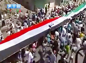 Imagem de canal de TV mostra srios em protesto com a nova e a antiga bandeira do pas, no distrito de Homs