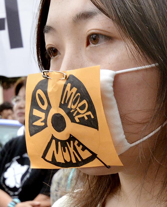 Manifestante japonesa usa mscara pedindo o fim da energia nuclear durante protestos em Tquio