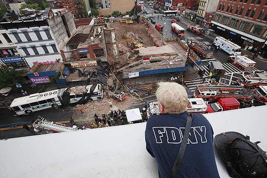 Bombeiro observa trabalho das equipes onde prédio caiu sobre um ônibus no Harlem, em Nova York 