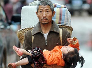 Chinês carrega menina ao desocupar a cidade de Guangan