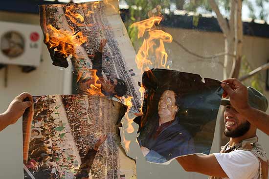 Combatentes rebeldes queimam imagens do ditador Muammar Gaddafi nas proximidades da cidade de Sirte