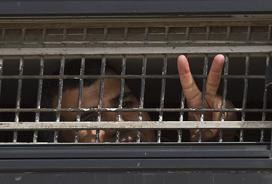 Prisioneiro palestino acena ao ser transferido para local onde será feita troca por israelense