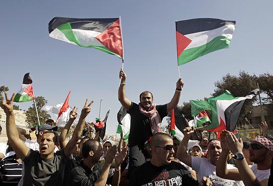 Palestino libertado Adnan Maragha (centro) carrega bandeiras enquanto  carregado no leste de Jerusalm