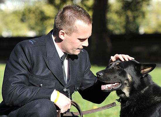 Cão policial chamado Obi ao lado de seu treinador; ele recebeu prêmio por atuação nos distúrbios de Londres
