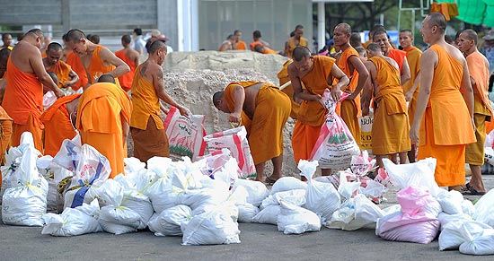 Monges tailandeses preparam sacos de areia para serem usados como barreira contra inundaes