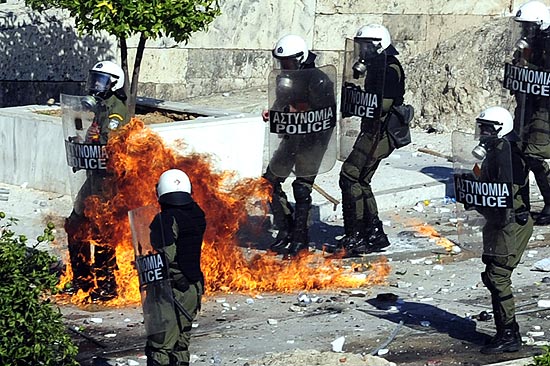Policiais gregos se protegem de ofensiva de manifestantes que participam de greve geral em Atenas