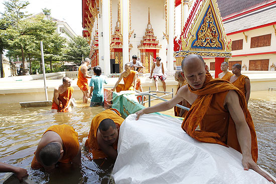 Monges budistas constroem barreira com sacos de areia depois de serem afetados por inundações