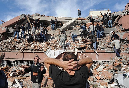 Moradores tentam auxiliar no resgate de presos sob escombros de um prédio na vila de Tabbani, próxima à cidade de Van