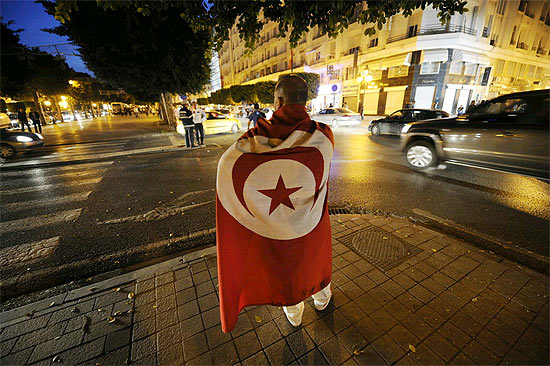 Tunisiano veste bandeira nacional enquanto caminha por avenida na cidade de Tnis