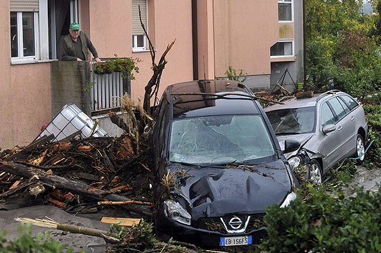 Homem observa carro destrudo aps tempestades que atingiram centro e norte da Itlia