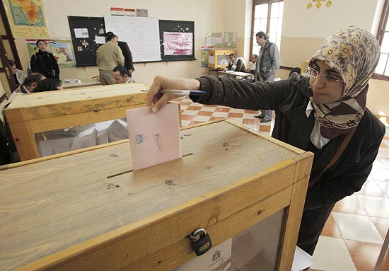 Mulher deposita cédula com voto na urna, no Cairo, durante a primeira eleição no Egito após a queda de Mubarak