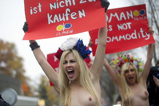 Seminuas, ativistas do grupo ucraniano Femen seguram faixa com os dizeres "mulher não é commodity"
