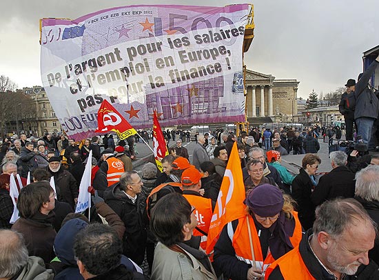 Manifestantes participantes de protestos levam cartazes em Paris contra medidas de austeridade