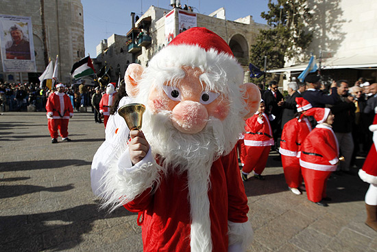 Pessoa vestida de Papai Noel toca sino em local próximo à Igreja da Natividade, em Israel