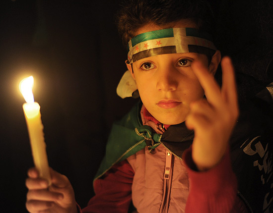 Garoto srio leva uma vela durante viglia no Cairo em apoio a manifestantes na Sria