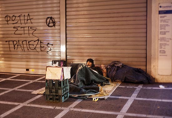 Homens dormem em praça na região central de Atenas; crise econômica tem feito pais colocarem seus filhos para adoção