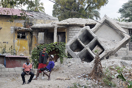 Moradores descansam em frente a uma casa destruda por terremoto no Haiti, quase dois anos mais tarde