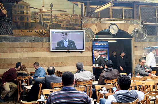 Srios assistem a discurso de Bashar Assad na TV dentro de estabelecimento comercial em Damasco