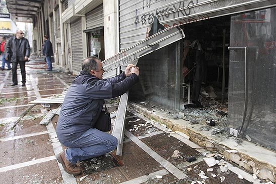 Homem observa danos causados por violentos confrontos em Atenas