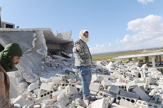 Homem anda sobre escombros de casas na cidade de Idlib, no norte da Síria, após ataque de regime
