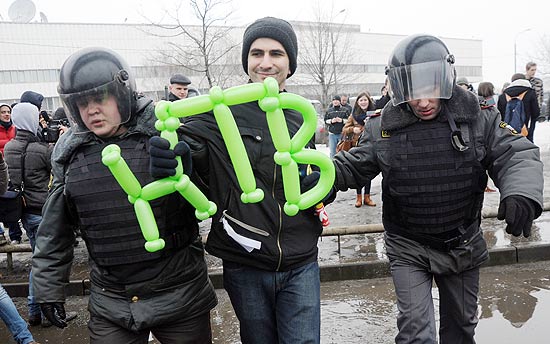 Manifestante carrega bales com as iniciais em russo do canal estatal, em protesto em Moscou