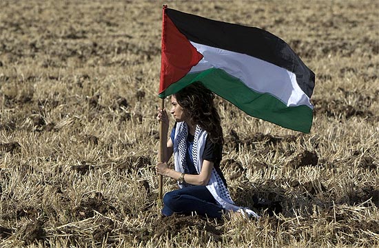 Uma manifestante rabe-israelense segura a bandeira da Palestina em Abu Snan
