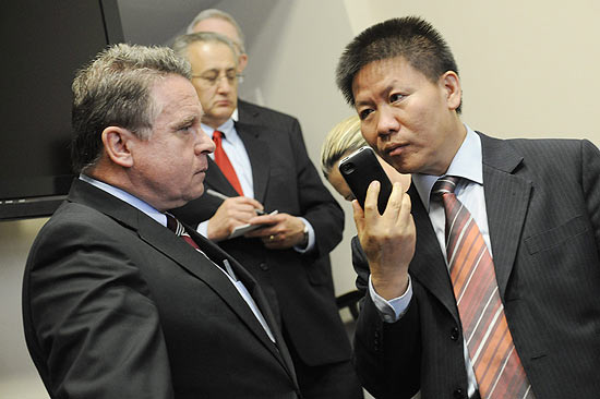 Bob Fu ( dir.) recebe telefonema do dissidente Chen ao lado do republicano Chris Smith 