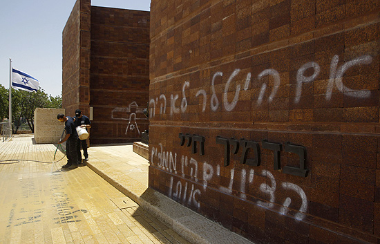 Trabalhadores limpam pichação no Museu do Holocausto, em Jerusalém