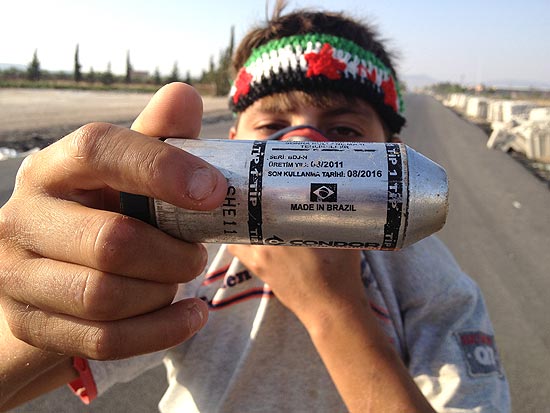 Menino sírio segura bomba de gás lacrimogêneo feita no Brasil usada em campo de refugiados na Turquia