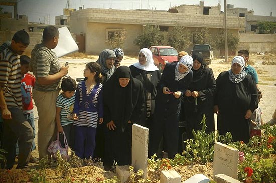 Mulheres rezam em frente aos tmulos de parentes mortos pelas foras do ditador srio Bashar Assad