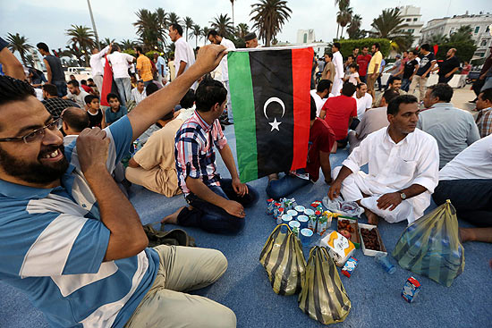 Homem segura bandeira líbia e comemora o primeiro aniversário, pelo calendário islâmico, da revolta contra Gaddafi