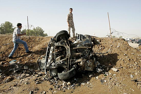 Homens observam carro que explodiu perto de uma companhia de petrleo, nas proximidades de Kirkuk