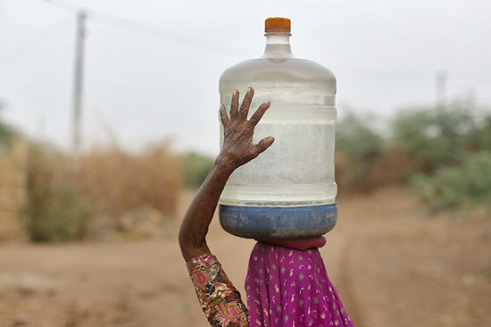 Mulher carrega galão de água na cabeça na cidade de Charanka, na Índia