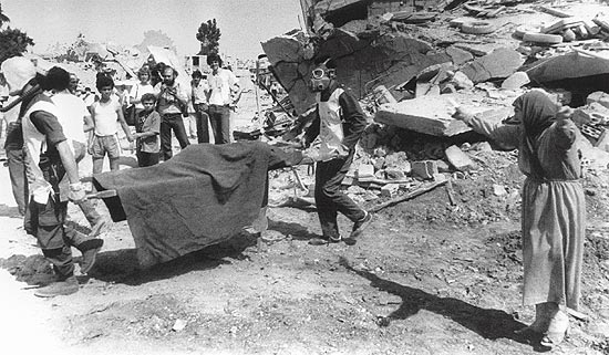Fotografia de 1982 mostra mulher chorando, enquanto homens retiram corpos de mortos do massacre de Sabra
