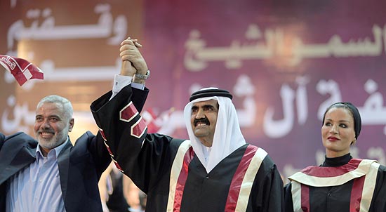 O emir do Qatar, Hamad bin Khalifa al Thani (centro), e o premiê Ismail Haniyeh (Hamas) erguem as mãos, em Gaza