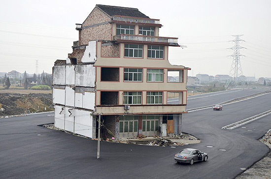 Carros têm de contornar prédio na cidade de Wenling, na China; casa foi demolida no fim de semana