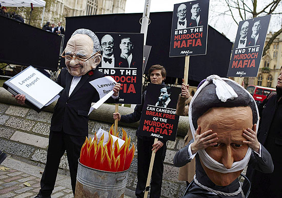 Manifestantes protestam com máscaras do premiê David Cameron e do magnata Rupert Murodch em Londres