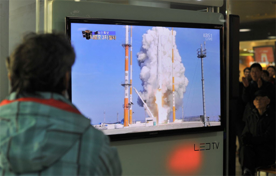 Homem observa pela televisão em estação de trem em Seul o lançamento do foguete espacial Naro