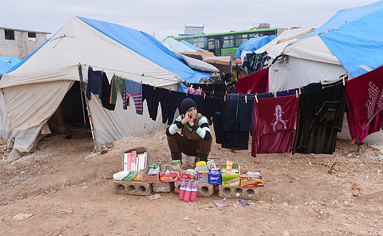 Srio vende produtos em frente a tenda de acampamento de refugiados prximo da fronteira com a Turquia