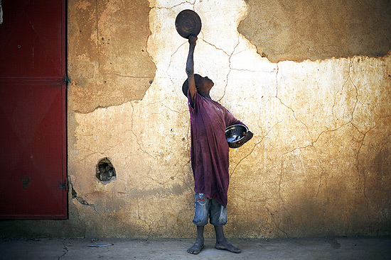Criança segura prato que usa para pedir comida em mercado de Gao, no Mali
