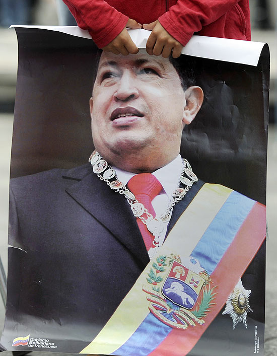 Garoto segura cartaz com foto de Chvez no ms passado, em Caracas
